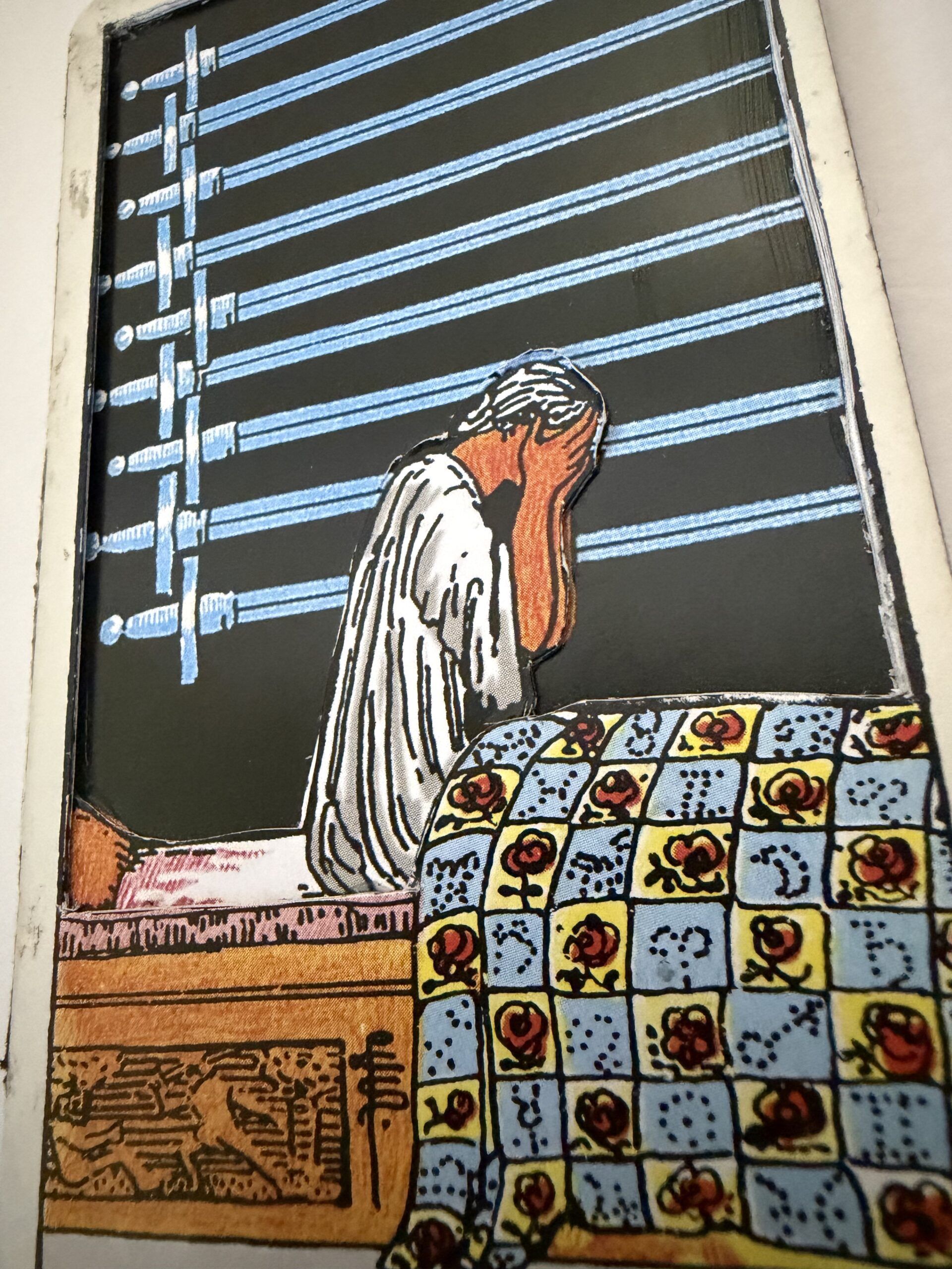 3D layered Nine of Swords tarot card with figure in distress sitting on bed